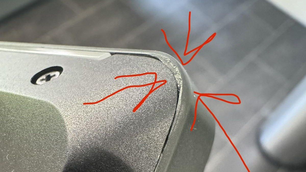 Close up of the damaged corner edge of the Lenovo Legion 7i with arrows pointing at the scraped metal