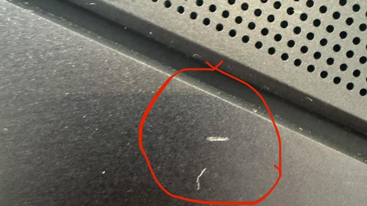 Scratch marks on the keyboard deck of the Lenovo Legion 7i laptop circled in red