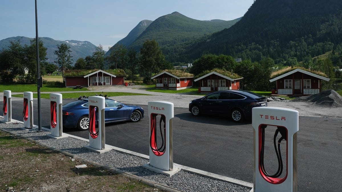 Electric cars at Tesla Supercharger station in Norway with mountains