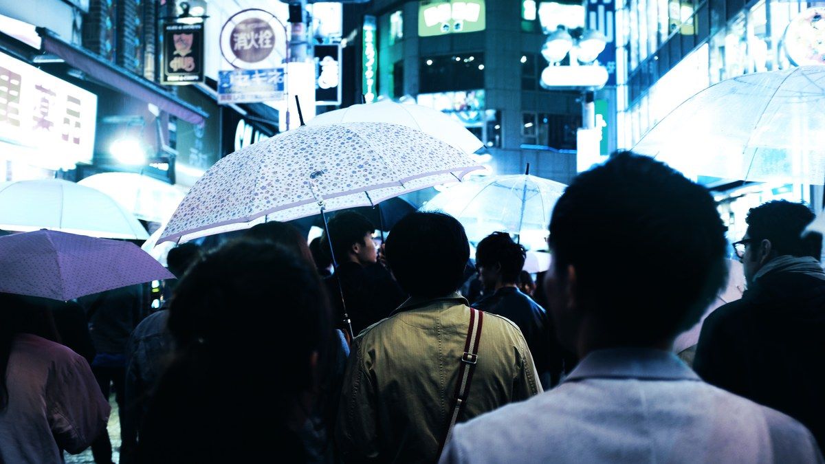 Crowd holding umbrellas on a Tokyo street at night during the Tokyo rainfall record rain