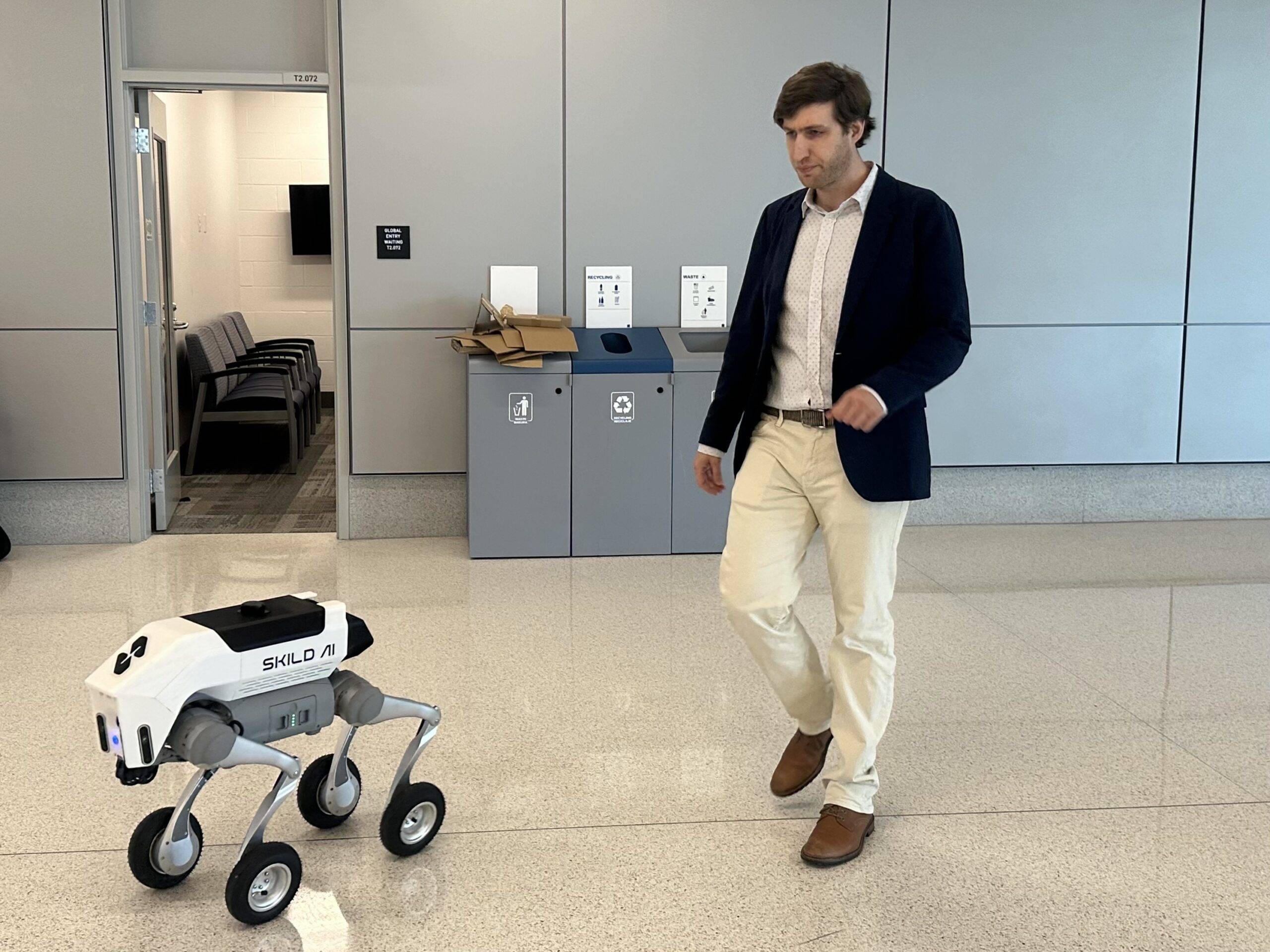 A Skild team member demonstrates a robot dog spotting an overflowing trash bin
